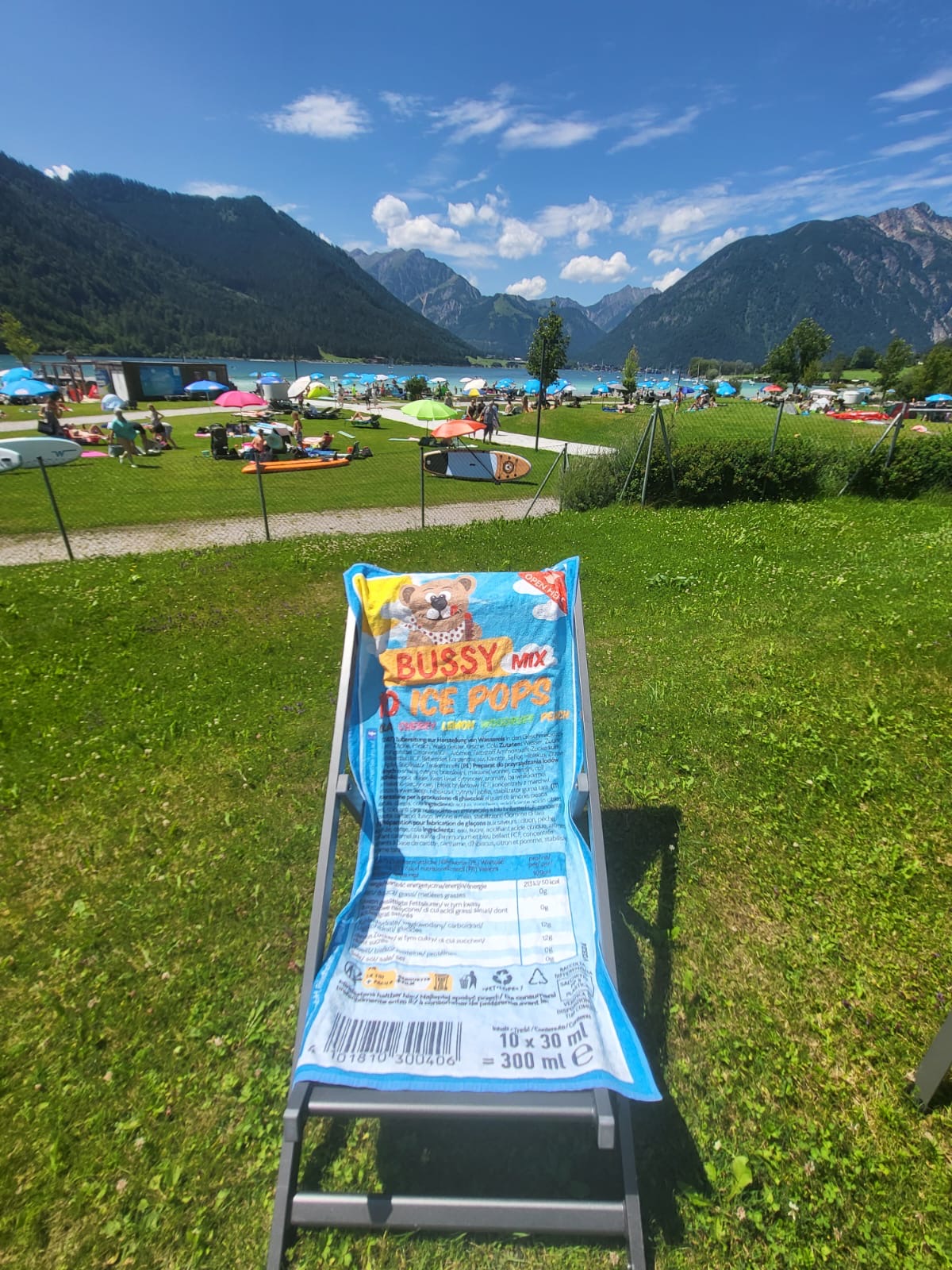 Das Bussyhandtuch an einem See mit Bergen im Hintergrund